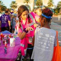 A Girls on the Run volunteer holds up a mirror to a participant who has face paint on